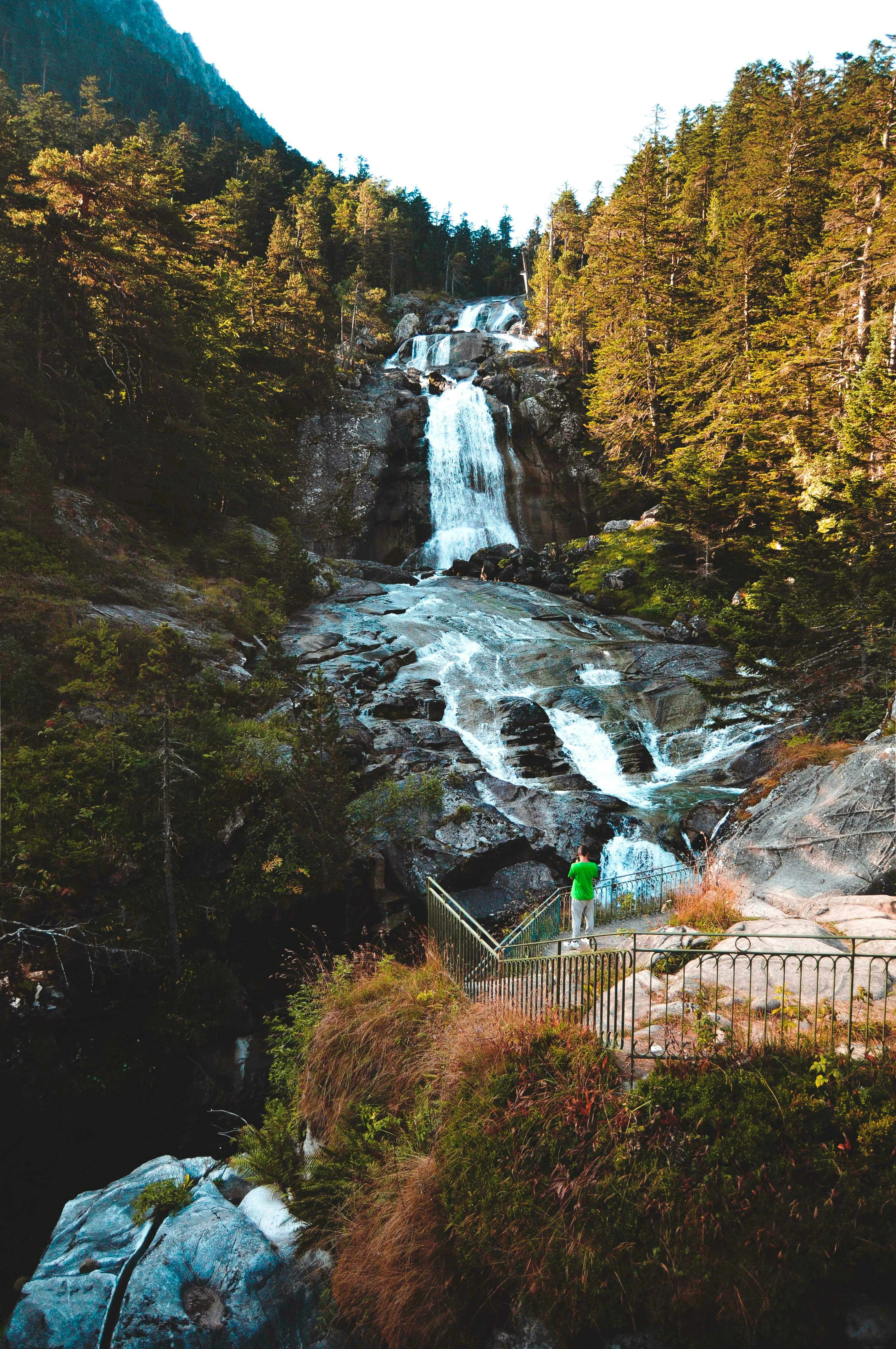 green metal fence near waterfalls during daytime